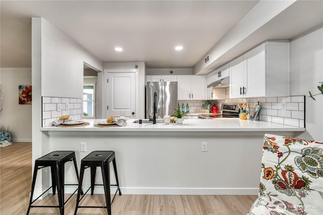 3939 10th St SE Unit C6, Puyallup, WA 98374 - kitchen with stainless steel appliances, under cabinet range hood, a peninsula, light countertops, and recessed lighting