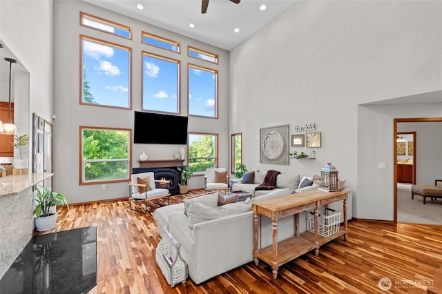 19838 Bear View Ln SW, Rochester, WA 98579 - living area featuring a high ceiling, ceiling fan, plenty of natural light, a warm lit fireplace, and wood finished floors