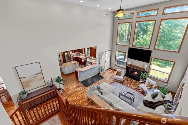 19838 Bear View Ln SW, Rochester, WA 98579 - living area featuring a high ceiling, wood finished floors, a ceiling fan, a warm lit fireplace, and recessed lighting