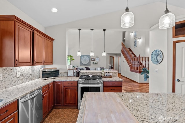 19838 Bear View Ln SW, Rochester, WA 98579 - kitchen with appliances with stainless steel finishes, lofted ceiling, a peninsula, light stone countertops, and decorative light fixtures