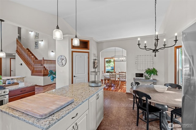 19838 Bear View Ln SW, Rochester, WA 98579 - kitchen featuring a chandelier, arched walkways, white cabinets, a center island, and light stone counters