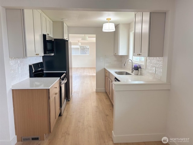 308 N Dale Rd, Moses Lake, WA 98837 - kitchen featuring range with electric stovetop, stainless steel microwave, light wood-type flooring, and decorative backsplash