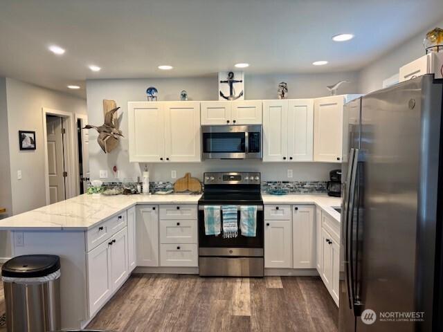 163 Wishkah St SW, Ocean Shores, WA 98569 - kitchen with appliances with stainless steel finishes, a peninsula, dark wood-type flooring, white cabinetry, and recessed lighting