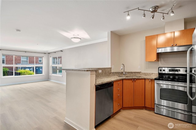 621 5th Ave N Unit 103, Seattle, WA 98109 - kitchen featuring appliances with stainless steel finishes, light wood-style flooring, under cabinet range hood, light stone counters, and a peninsula