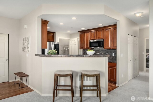 1855 Trossachs Blvd SE Unit 1401, Sammamish, WA 98075 - kitchen with stainless steel appliances, a breakfast bar, dark countertops, tasteful backsplash, and a peninsula