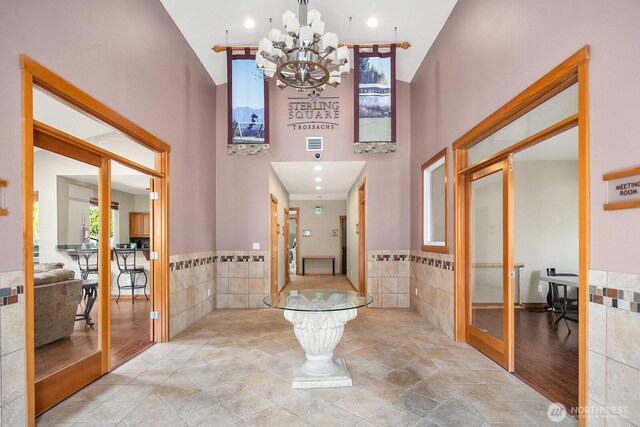 1855 Trossachs Blvd SE Unit 1401, Sammamish, WA 98075 - hallway featuring a towering ceiling, tile walls, a chandelier, wainscoting, and recessed lighting