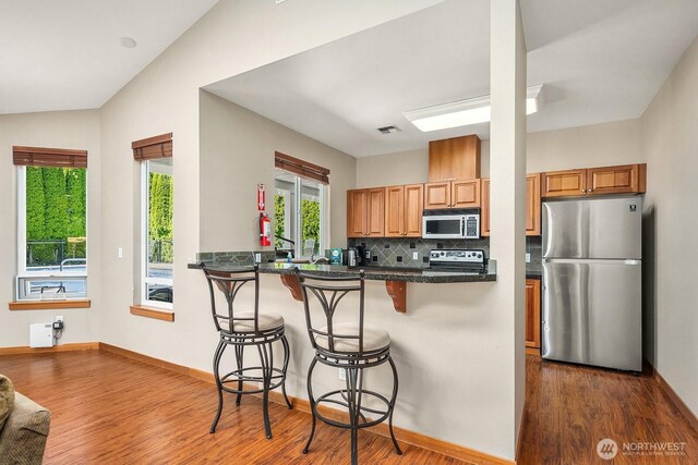 1855 Trossachs Blvd SE Unit 1401, Sammamish, WA 98075 - kitchen with appliances with stainless steel finishes, dark wood-type flooring, a breakfast bar area, tasteful backsplash, and dark countertops