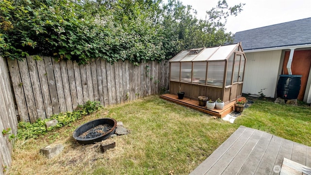 1215 273rd Pl, Ocean Park, WA 98640 - fenced backyard featuring a greenhouse, an outdoor structure, a fire pit, and a deck