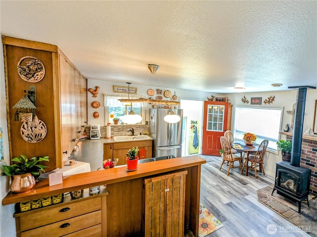 1215 273rd Pl, Ocean Park, WA 98640 - kitchen with freestanding refrigerator, a wood stove, brown cabinets, a textured ceiling, and light wood finished floors