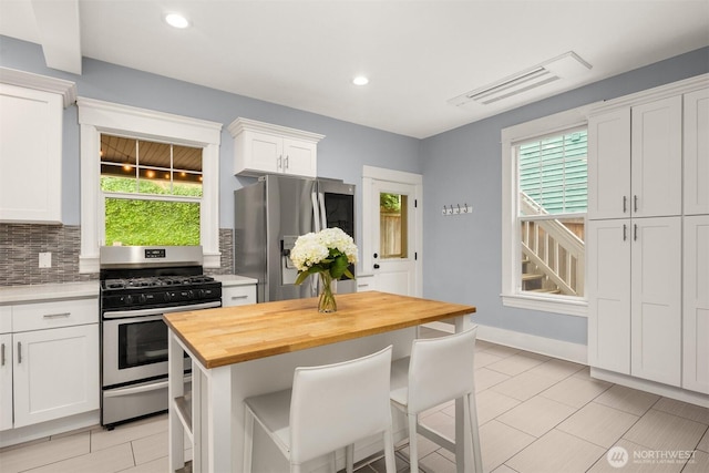 325 23rd Ave E, Seattle, WA 98112 - kitchen with stainless steel appliances, wooden counters, decorative backsplash, white cabinets, and recessed lighting
