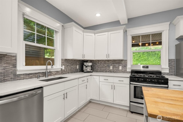 325 23rd Ave E, Seattle, WA 98112 - kitchen with stainless steel appliances, butcher block counters, light tile patterned flooring, backsplash, and beam ceiling