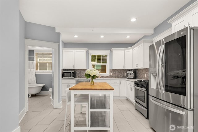 325 23rd Ave E, Seattle, WA 98112 - kitchen featuring stainless steel appliances, decorative backsplash, butcher block counters, white cabinets, and recessed lighting