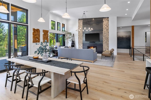 3847 Swiftwater Dr, Cle Elum, WA 98922 - dining room featuring light wood-style flooring, recessed lighting, a fireplace, a towering ceiling, and a chandelier