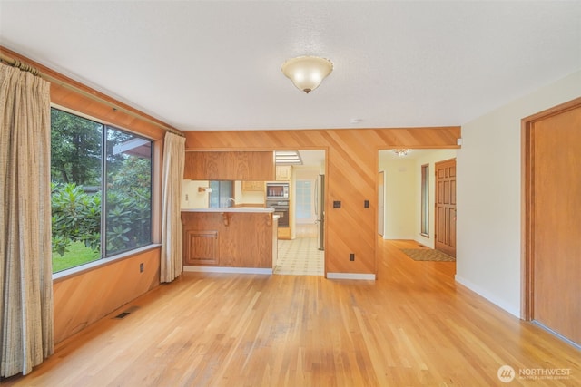 2004 SW 306th Pl, Federal Way, WA 98023 - kitchen featuring stainless steel microwave, light wood-style floors, a peninsula, oven, and brown cabinets