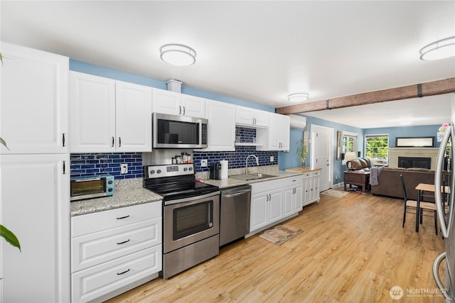 5636 N 40th St, Tacoma, WA 98407 - kitchen featuring appliances with stainless steel finishes, backsplash, light wood-style floors, and white cabinetry