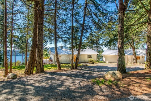 339 Highlands Dr, Orcas Island, WA 98245 - view of front facade featuring gravel driveway, a metal roof, a chimney, and a water view