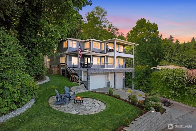 3811 N Dale St, Tacoma, WA 98407 - back of house at dusk featuring a balcony, stairs, a lawn, a garage, and concrete driveway