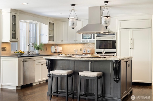 8234 NE 8th St, Medina, WA 98039 - kitchen featuring wall chimney exhaust hood, glass insert cabinets, dark wood-style floors, backsplash, and a kitchen bar