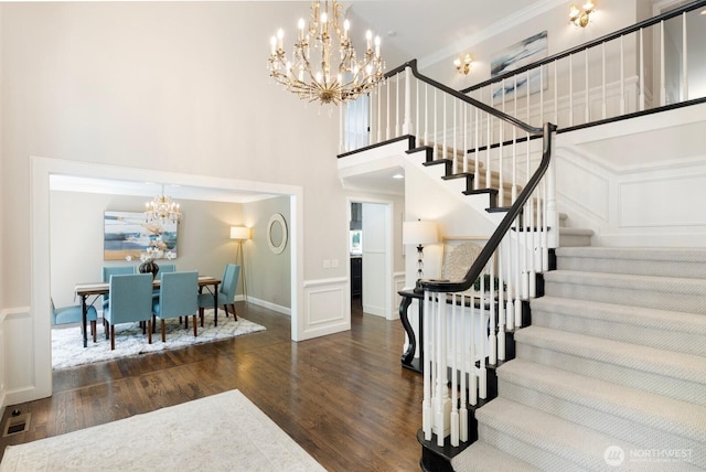 8234 NE 8th St, Medina, WA 98039 - staircase featuring a chandelier, wood finished floors, a decorative wall, a towering ceiling, and ornamental molding