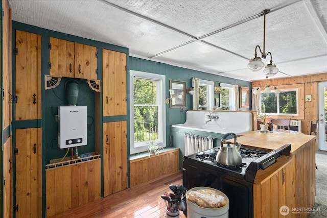 48911 Mountain Loop Hwy, Granite Falls, WA 98252 - kitchen featuring light wood-style floors, wood walls, tankless water heater, brown cabinetry, and hanging light fixtures
