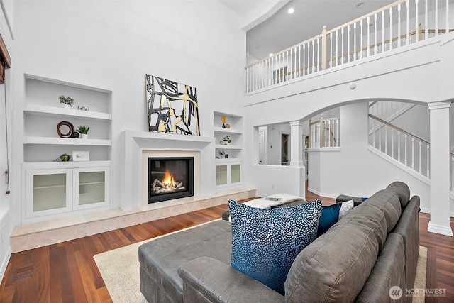 1402 180th Ave E, Lake Tapps, WA 98391 - living area with built in features, a high end fireplace, decorative columns, wood finished floors, and a towering ceiling