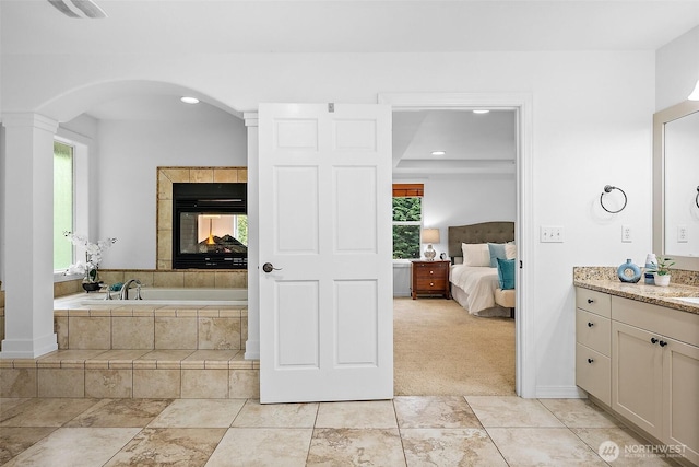 1402 180th Ave E, Lake Tapps, WA 98391 - ensuite bathroom featuring vanity, a bath, ornate columns, recessed lighting, and a tile fireplace