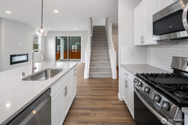544 SW 97th St Unit 5, Seattle, WA 98106 - kitchen featuring appliances with stainless steel finishes, dark wood-style floors, white cabinetry, pendant lighting, and backsplash