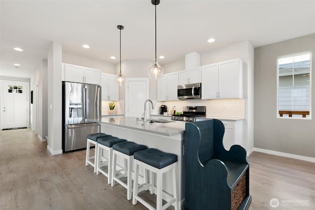 9898 5th Ln SW Unit 23, Seattle, WA 98106 - kitchen with appliances with stainless steel finishes, decorative backsplash, light wood-type flooring, light countertops, and a kitchen bar