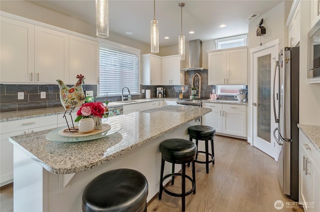 24220 93rd Ct S, Kent, WA 98030 - kitchen with wall chimney range hood, freestanding refrigerator, a kitchen breakfast bar, light wood-type flooring, and white cabinetry