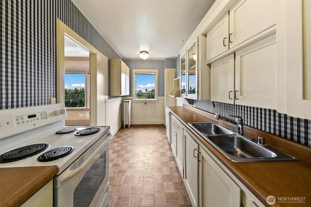 1902 Bigelow Ave N Unit 301, Seattle, WA 98109 - kitchen with white range with electric cooktop, wallpapered walls, dark countertops, and glass insert cabinets