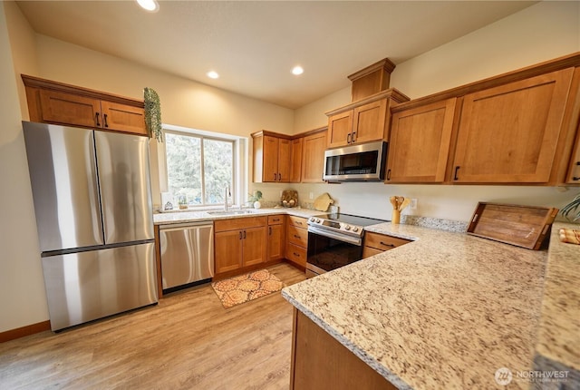 121 Stafford St, Leavenworth, WA 98826 - kitchen featuring stainless steel appliances, light wood-type flooring, recessed lighting, brown cabinetry, and light stone countertops