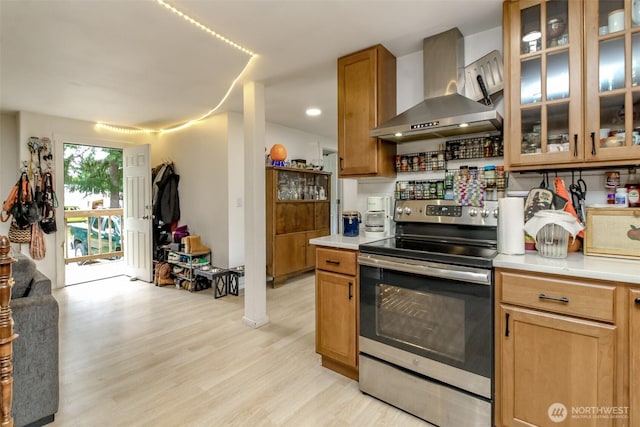 8715 Whitewood Loop SE, Yelm, WA 98597 - kitchen featuring wall chimney exhaust hood, electric stove, light countertops, light wood-style floors, and glass insert cabinets