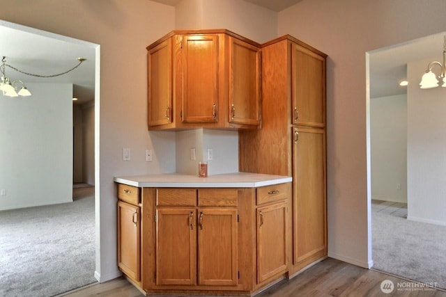 4018 144th Street Ct NW Unit 59, Gig Harbor, WA 98332 - kitchen with light colored carpet, light countertops, brown cabinetry, a chandelier, and light wood-type flooring