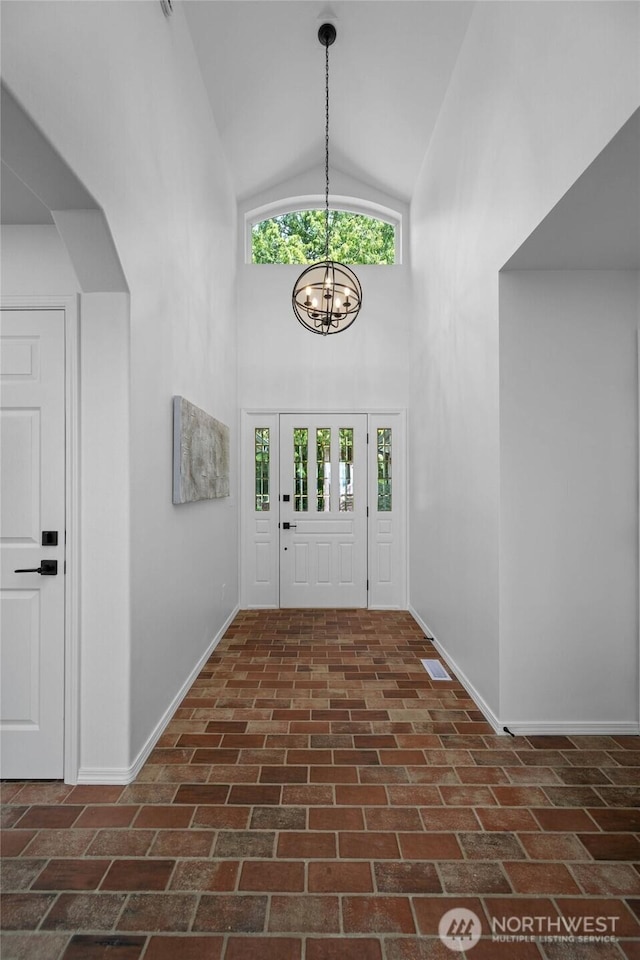 3995 Bay Ln, Anacortes, WA 98221 - entrance foyer with plenty of natural light, a chandelier, high vaulted ceiling, and brick patterned flooring