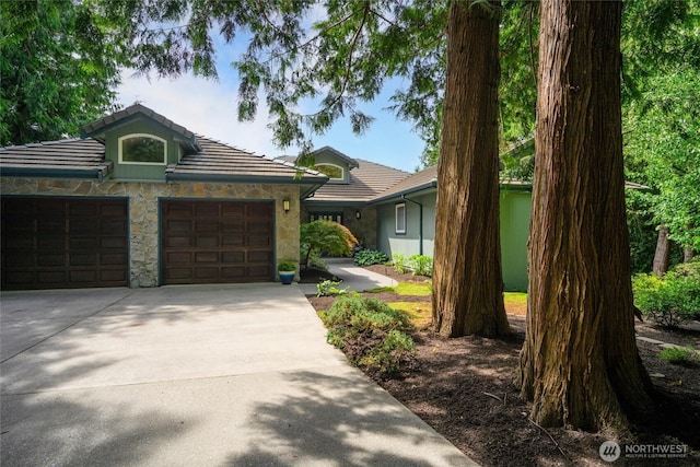 3995 Bay Ln, Anacortes, WA 98221 - view of front of property with concrete driveway, stone siding, an attached garage, and a tile roof