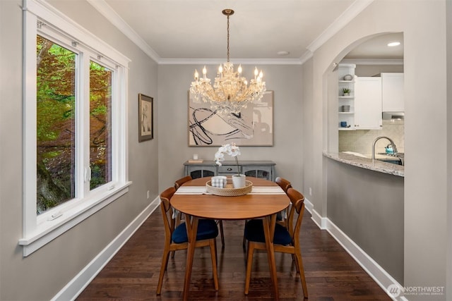 3833 24th Ave W, Seattle, WA 98199 - dining room featuring crown molding, dark wood-style flooring, a chandelier, and arched walkways