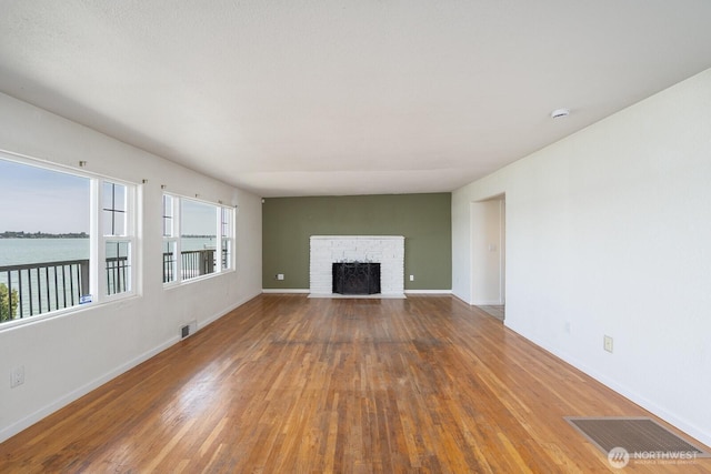 2497 Westshore Dr NE, Moses Lake, WA 98837 - unfurnished living room with wood finished floors, a fireplace, and a water view