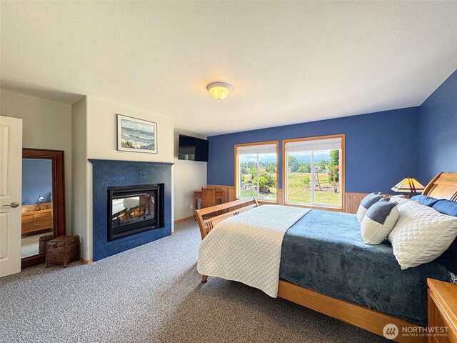 206 Buckhorn, Sequim, WA 98382 - bedroom featuring carpet flooring, a multi sided fireplace, and a wainscoted wall
