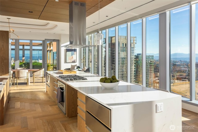 800 Columbia St Unit 708, Seattle, WA 98104 - kitchen with island exhaust hood, modern cabinets, a large island, appliances with stainless steel finishes, and brown cabinetry