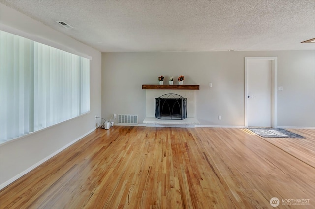 30004 5th Ave SW, Federal Way, WA 98023 - unfurnished living room featuring a textured ceiling, wood finished floors, and a fireplace with raised hearth