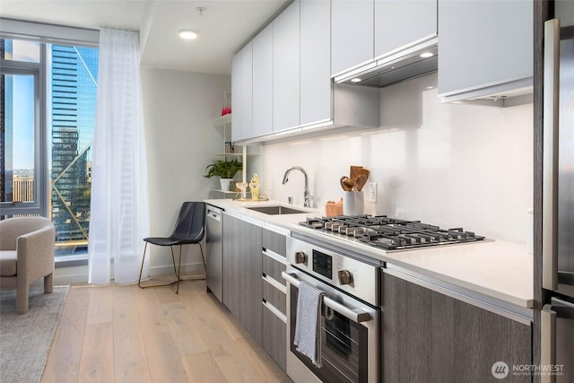 800 Columbia St Unit 1009, Seattle, WA 98104 - kitchen featuring range hood, light wood-type flooring, light countertops, white cabinets, and modern cabinets