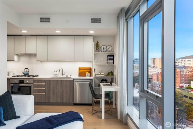 800 Columbia St Unit 1708, Seattle, WA 98104 - kitchen featuring appliances with stainless steel finishes, light wood-type flooring, plenty of natural light, and modern cabinets