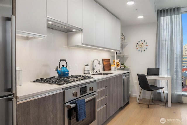 800 Columbia St Unit 1708, Seattle, WA 98104 - kitchen with stainless steel appliances, extractor fan, light wood-type flooring, white cabinets, and light countertops