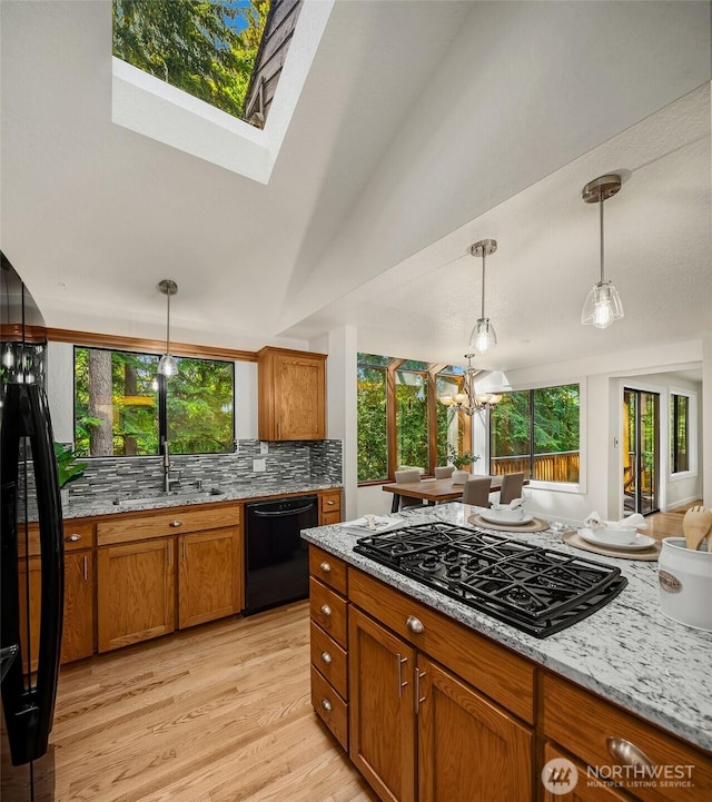 1820 NE 177th St, Shoreline, WA 98155 - kitchen featuring black appliances, brown cabinets, light stone counters, light wood-type flooring, and pendant lighting