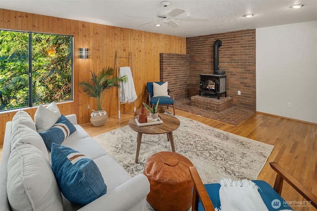 1820 NE 177th St, Shoreline, WA 98155 - living room with a wood stove, ceiling fan, wood walls, and wood finished floors