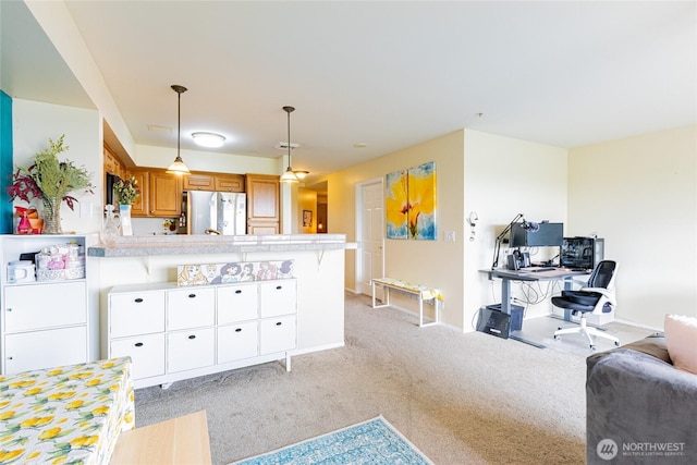 3201 Pacific Ave Unit 403, Tacoma, WA 98418 - kitchen featuring freestanding refrigerator, brown cabinets, a peninsula, light carpet, and light countertops