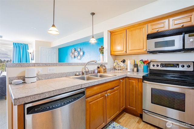 3201 Pacific Ave Unit 403, Tacoma, WA 98418 - kitchen featuring appliances with stainless steel finishes, tile countertops, a peninsula, light wood-style flooring, and hanging light fixtures