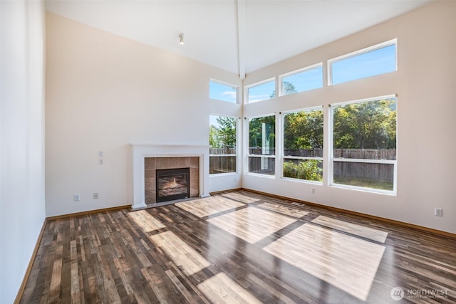 807 Williams St NW, Orting, WA 98360 - unfurnished living room featuring wood finished floors, a tile fireplace, and a towering ceiling