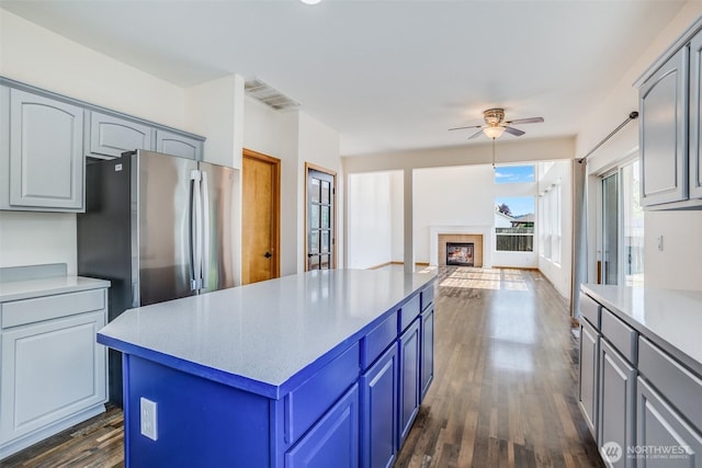 807 Williams St NW, Orting, WA 98360 - kitchen with freestanding refrigerator, a ceiling fan, dark wood-type flooring, light countertops, and a center island