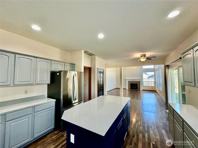 807 Williams St NW, Orting, WA 98360 - kitchen with freestanding refrigerator, ceiling fan, a kitchen island, light countertops, and dark wood-style flooring